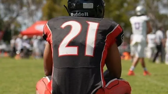 Spartans number 21 crouches on the sideline, watching the play